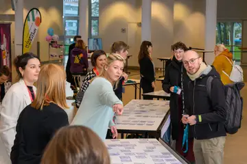 Mehrere Personen stehen an Tischen bei der Anmeldung zum Forum Wissenschaftskommunikation im Eingangsbereich der Stadthalle.