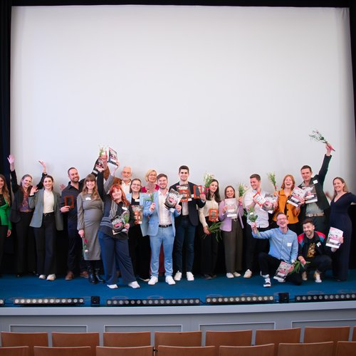 Gruppe von Personen die Jubeln und Blumen und Trophäen präsentieren