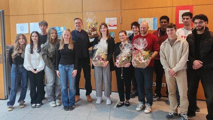 Gruppenbild mit 14 Personen, vier davon halten einen Präsentkorb.