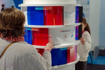 Ausstellung auf der MS Wissenschaft zum Thema Medizin der Zukunft. Exponat zur geschlechtersensiblen Medizin. Informationen zum heutigen Stand der Medizin und zur geschlechtersensiblen Medizin werden durch eine blaue oder eine rote Folie gefiltert.