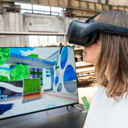 Eine Person an einem Exponat in einer Ausstellung. Die Person trägt eine VR-Brille.