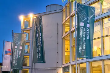 Die Stadthalle Bielefeld von außen. Vor der Halle sind Flaggen mit dem Logo des fwk aufgehängt.