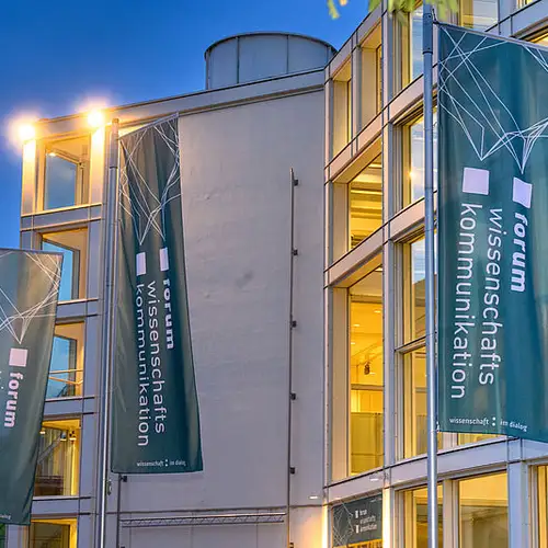 Die Stadthalle Bielefeld von außen. Vor der Halle sind Flaggen mit dem Logo des fwk aufgehängt.