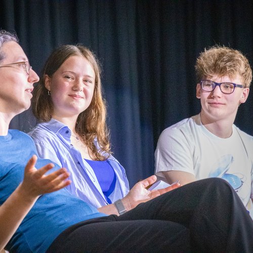 Schüler*innen und Forscherin im Gespräch auf Bühne
