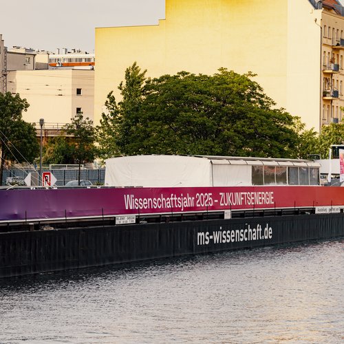 MS Wissenschaft liegt auf Fluss inmitten in Stadt