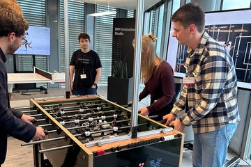 Personen an einem Kicker