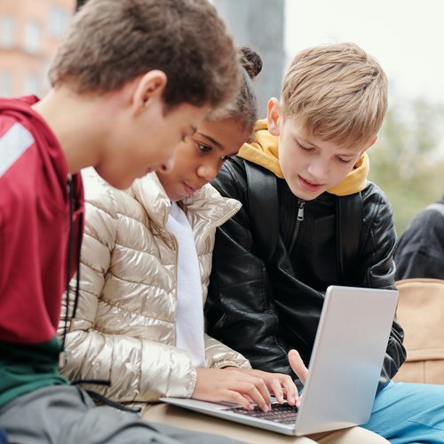 Schulkinder schauen zusammen auf Laptop