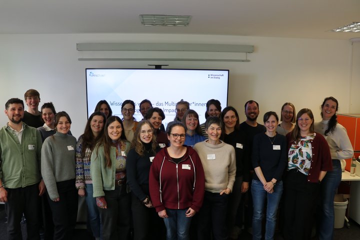 Ein Gruppenbild mit dem Projektteam der Impact Unit und den Teilnehmenden des Multiplikator*innenprogramms. Die 20 Personen stehen zusammen vor einer Präsentationsfolie und schauen lächelnd nach vorne.