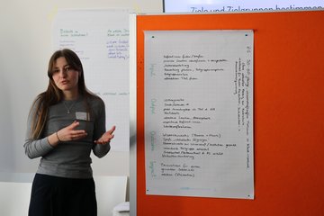 Eine Teilnehmerin präsentiert die Ergebnisse ihrer Gruppe vor der ganzen Runde.