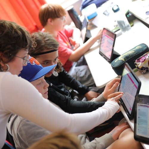 Betreuerin zeigt Schülern etwas auf Tablet bei I'm a Scientist