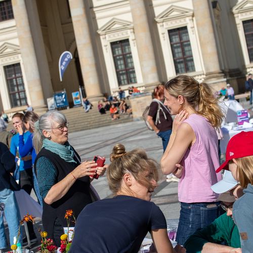 Viele Personen im Gespräch auf Gendarmenmarkt, herzliche Stimmung bei Sonne