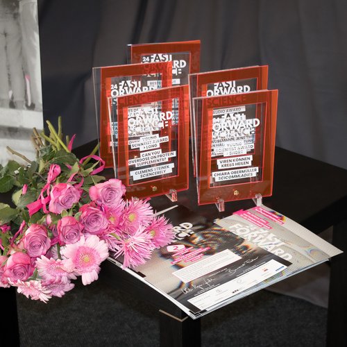 Fünf Pokale von Fast Forward Science und Blumen auf einem Tisch