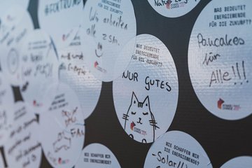 Detailaufnahme der Rückwand des Energiemobils. In der Mitte ein Sticker mit der Aufschrift "Was bedeutet Energiewende für die Zukunft? Nur Gutes" und der Skizze einer Katze.