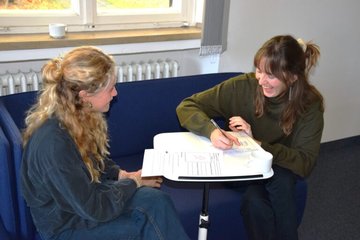 Zwei Personen bearbeiten lachend eine gemeinsame Aufgabe