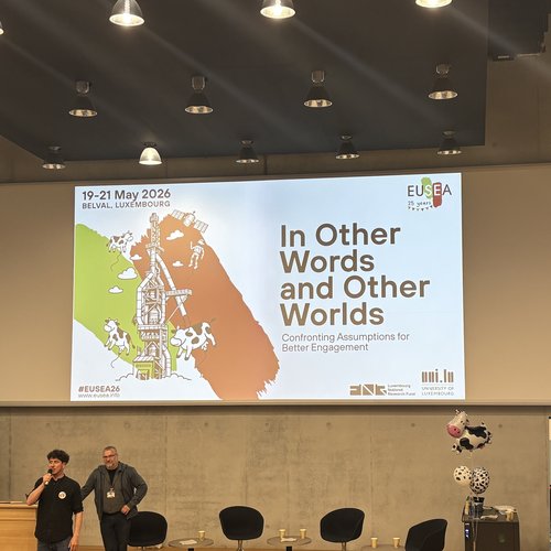Blick in einen Konferenzraum. Projektion an der Wand: 19-21 May 2026, Belval Luxembourg, #EUSEA26, www.eusea.info, In Other Words and Other Worlds Confronting Assuptions for Better Engagement.