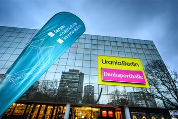 Außenansicht der Urania, im Vordergrund ein Aufsteller mit der Aufschrift "Forum Wissenschaftskommunikation"