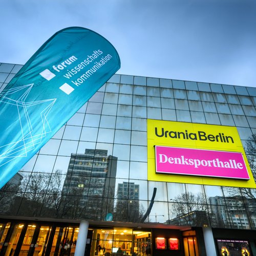 Außenansicht der Urania, im Vordergrund ein Aufsteller mit der Aufschrift "Forum Wissenschaftskommunikation"