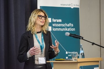 Person hält Vortrag vor Forum Wissenschaftskommunikation 2025 Banner