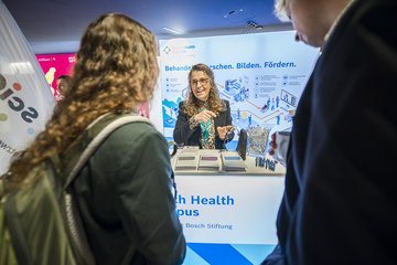 Personen unterhalten sich an Ausstellertisch