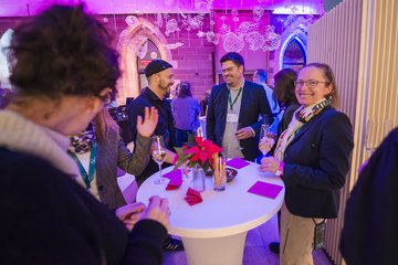 Personen am Stehtisch bei Abendveranstaltung