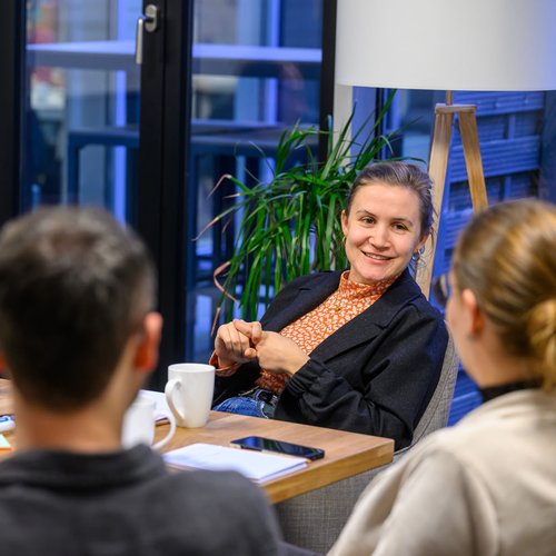 Vier Personen sitzen im Gespräch um Tisch