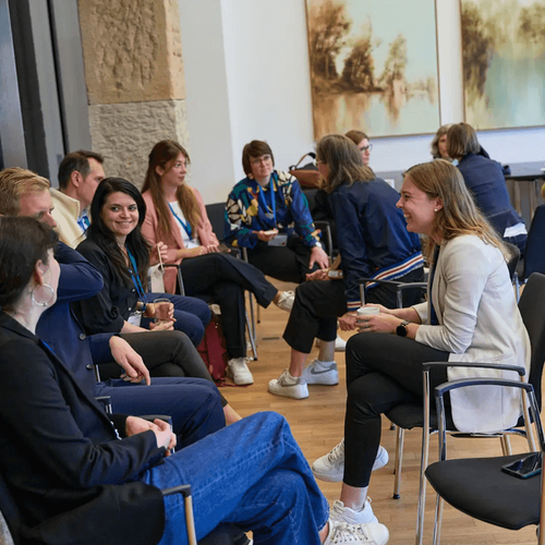 Personen sitzen in Raum zusammen und unterhalten sich