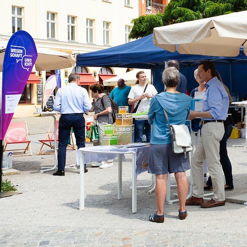 Personen in Kleingruppen im Gespräch auf Marktplatz