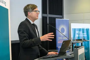 Ein Mann steht am Redepult und hält einen Vortrag.