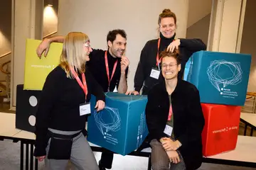 Vier Personen stehen zusammen und lachen.