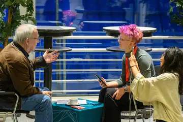 Zwei Frauen sitzen einem Mann gegenüber und interviewen ihn.