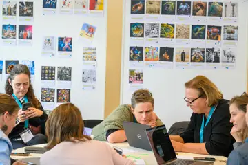 Personen sitzen an einem Tisch und Laptops zusammen und arbeiten