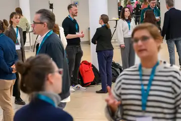 Menschen stehen jeweils zu zweit zusammen und unterhalten sich.