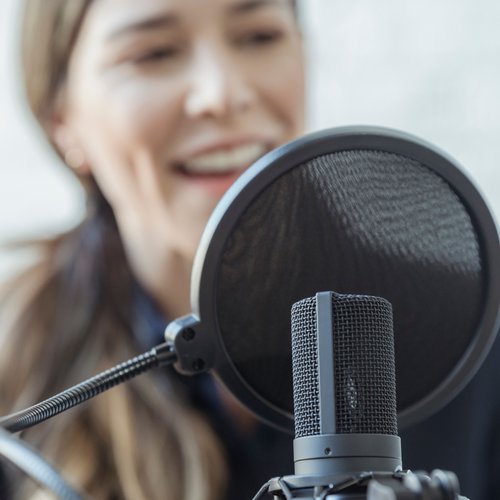Frau spricht in Podcastmikrofon
